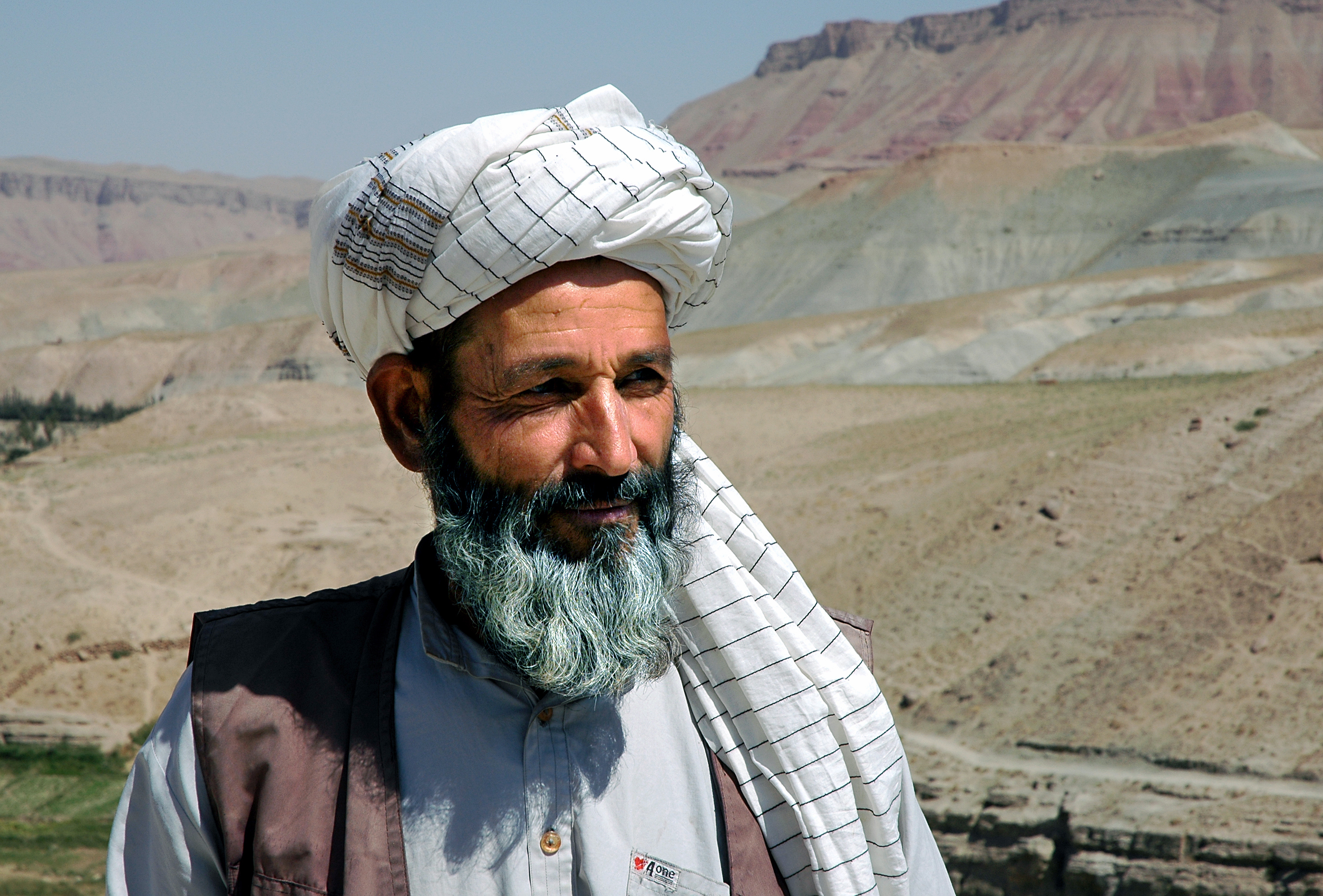Village between Herat and Qala-e-Naw, Herat Province / Afghanistan. A local Afghan man wearing a turban with a backdrop of mountain scenery in a remote part of western Afghanistan